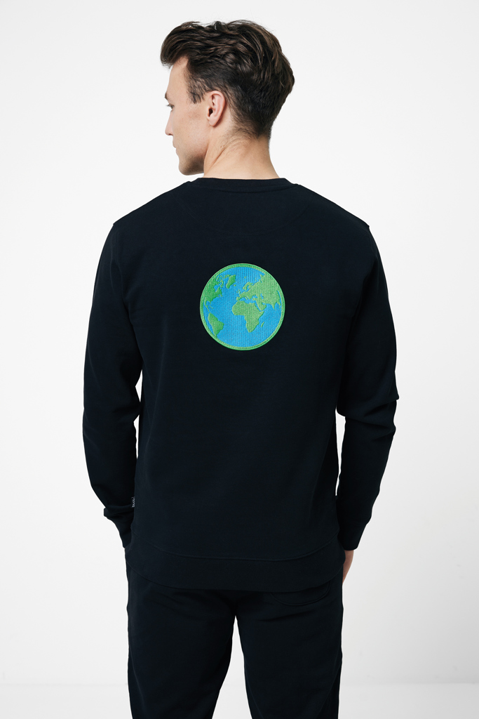 Homme portant un sweat noir avec globe terrestre.
