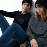 Couple en sweat et bonnet noir assis au sol