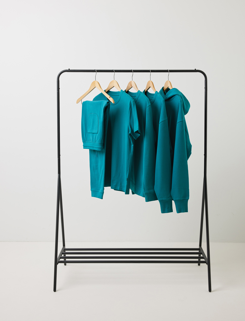 Vêtements turquoise suspendus sur un portant noir.