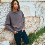 Personne portant un sweat gris contre un mur ancien