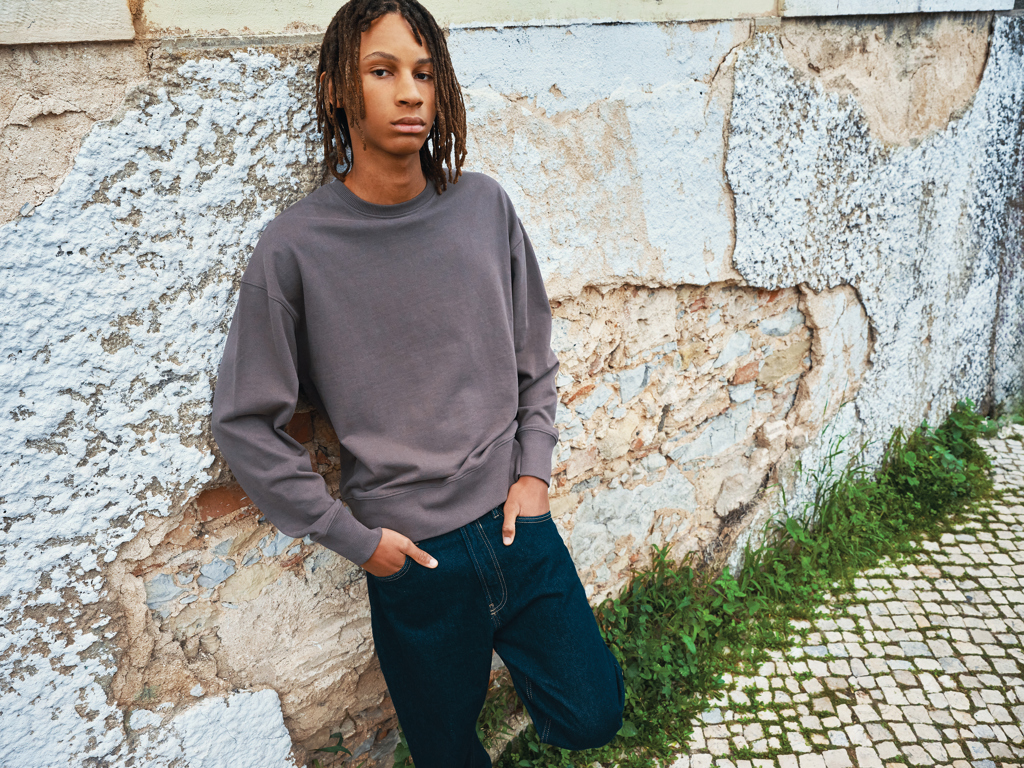Personne portant un sweat gris contre un mur ancien