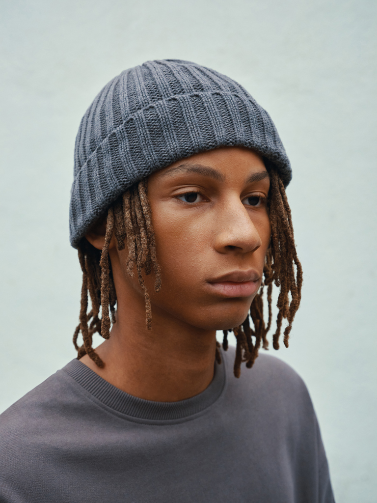 Personne portant un bonnet gris et un pull gris.