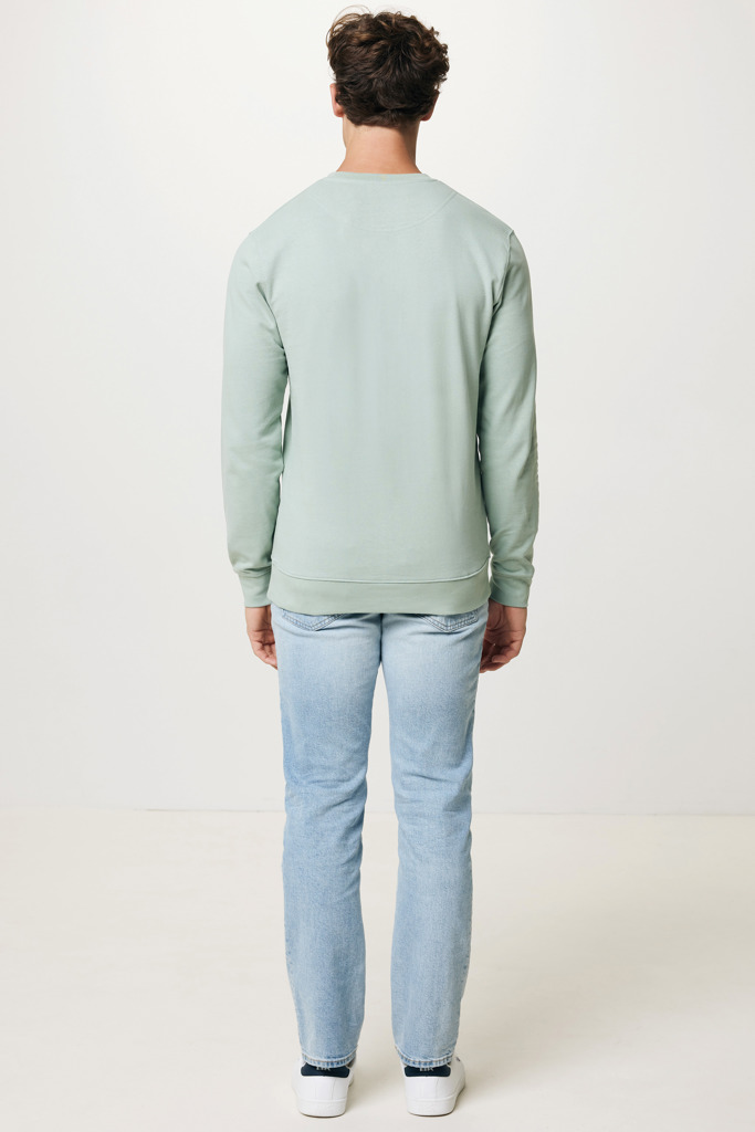 Homme portant un pull vert et un jean clair