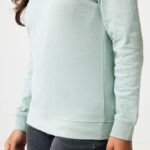 Personne portant un sweat vert clair et jean noir