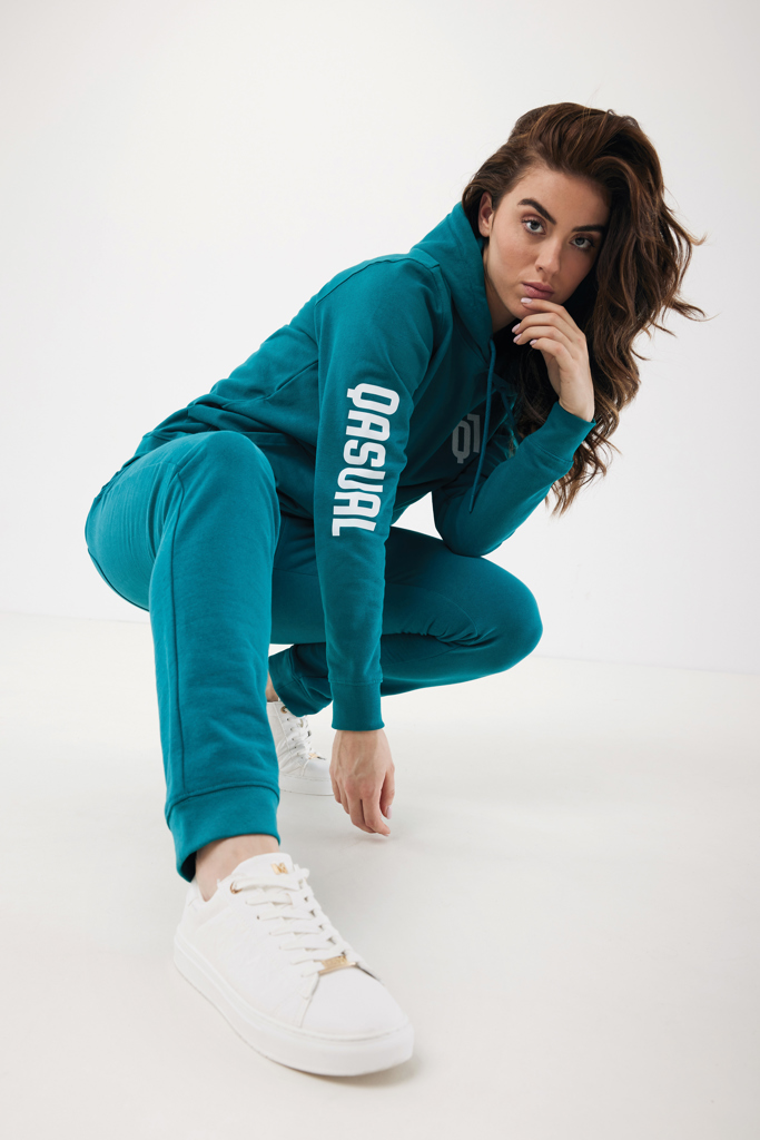 Femme en survêtement turquoise et baskets blanches