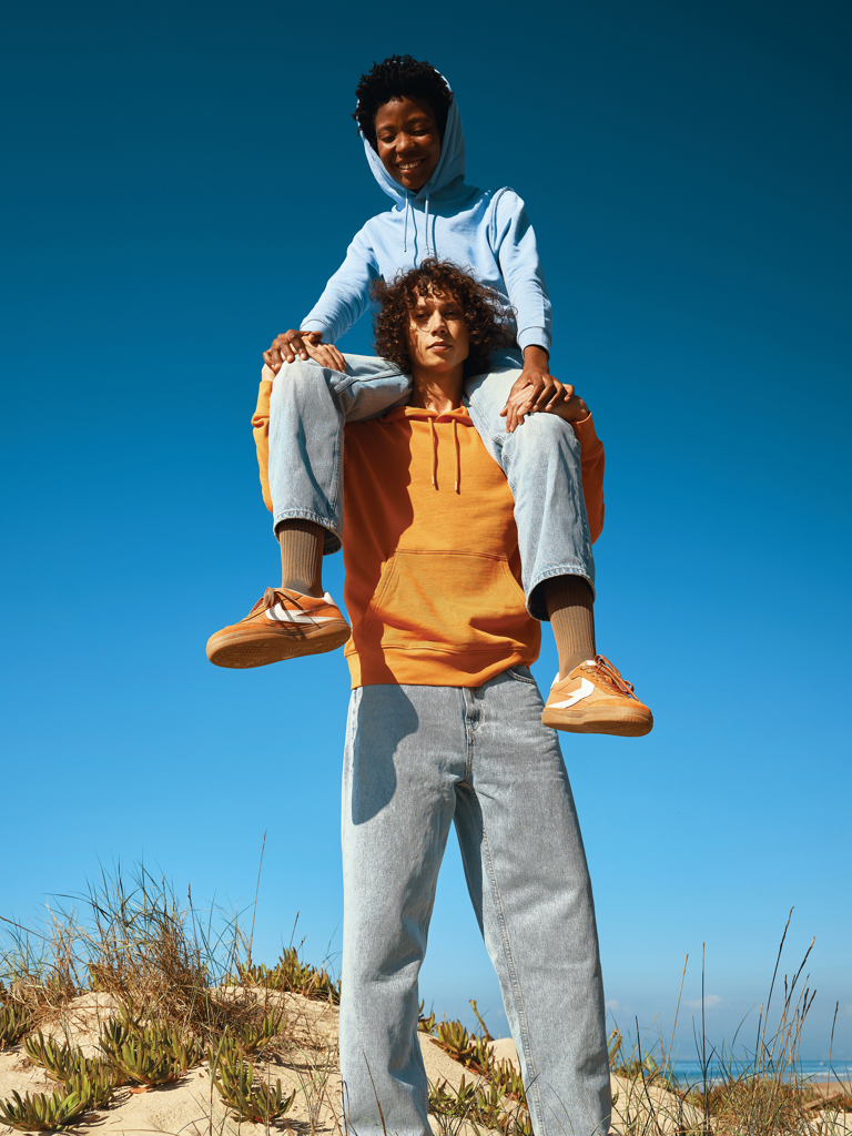 Deux amis souriants sur la plage, ciel bleu