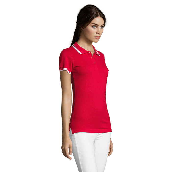 Femme portant un polo rouge et pantalon blanc