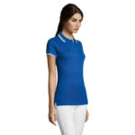 Femme portant un polo bleu et pantalon blanc