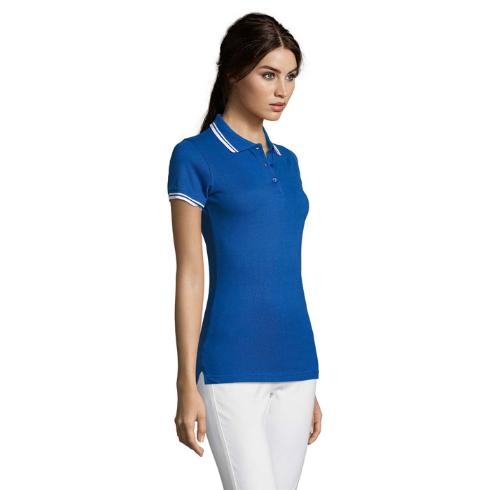 Femme portant un polo bleu et pantalon blanc