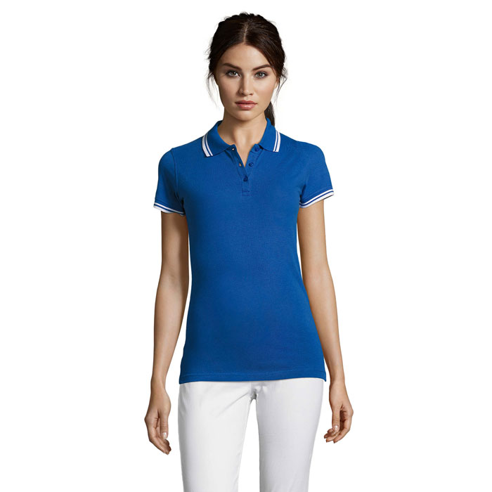 Femme portant un polo bleu et pantalon blanc