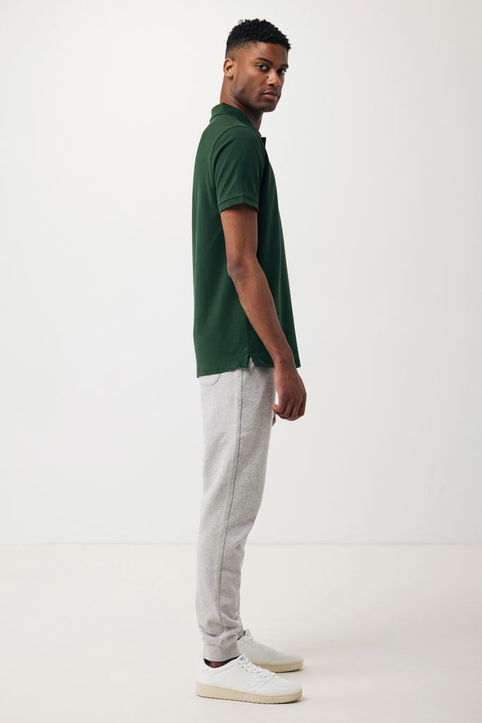 Homme portant polo vert et pantalon gris clair
