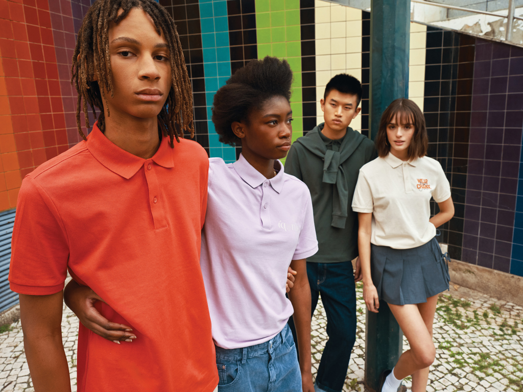 Jeunes portant des polos colorés devant un mur mosaïque.