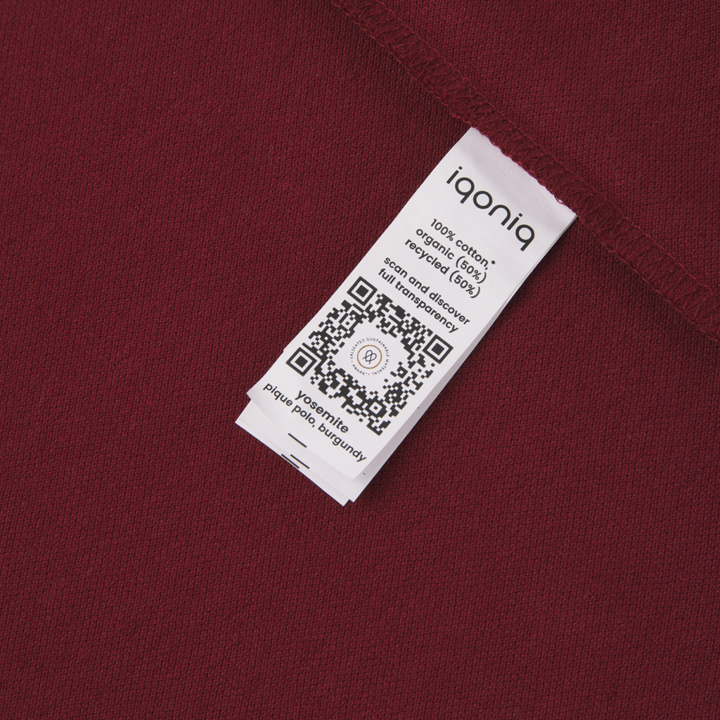 Étiquette blanche sur tissu bordeaux avec QR code.