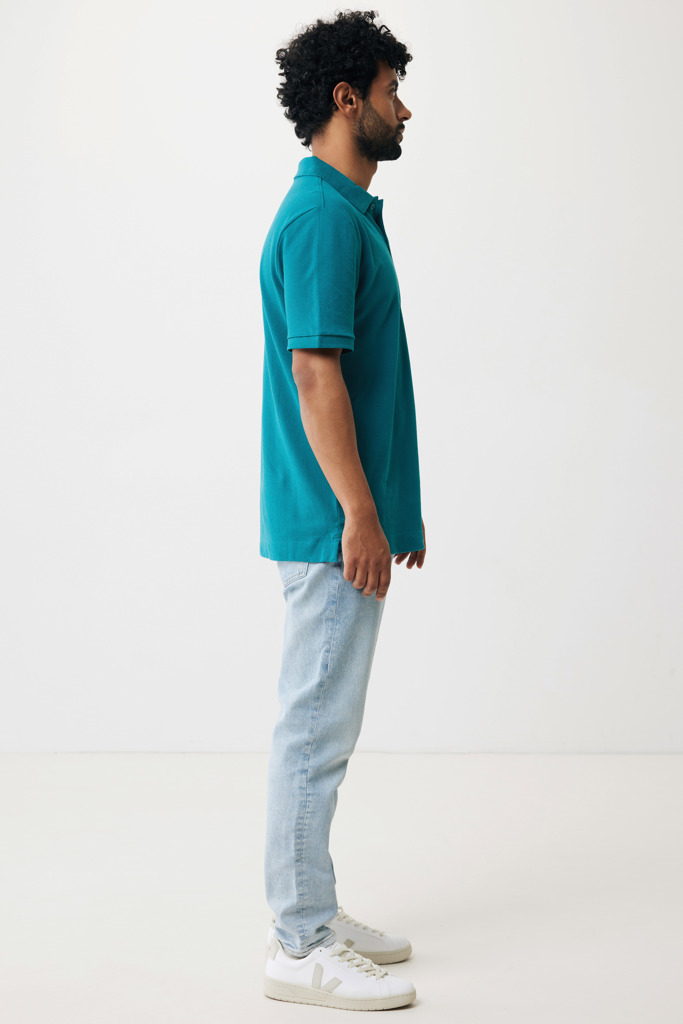Homme portant polo turquoise et jean clair.