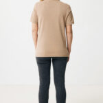 Femme portant polo beige et jean noir.