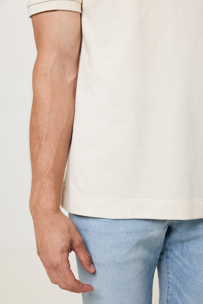 Main près d’un jean bleu et polo beige