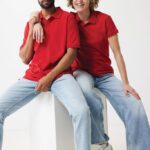 Deux personnes portent polos rouges et jeans clairs.