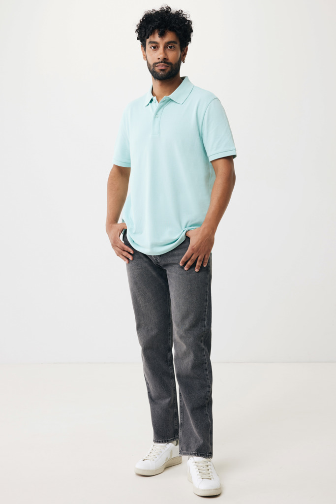 Homme portant polo bleu clair et jean gris.