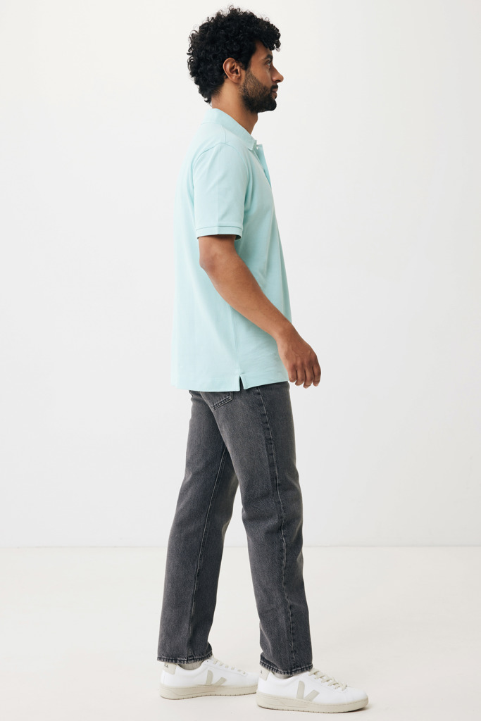 Homme portant un polo bleu et jean gris.