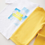 T-shirt blanc et sweat jaune posés côte à côte.