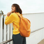 Personne souriante avec sac à dos orange