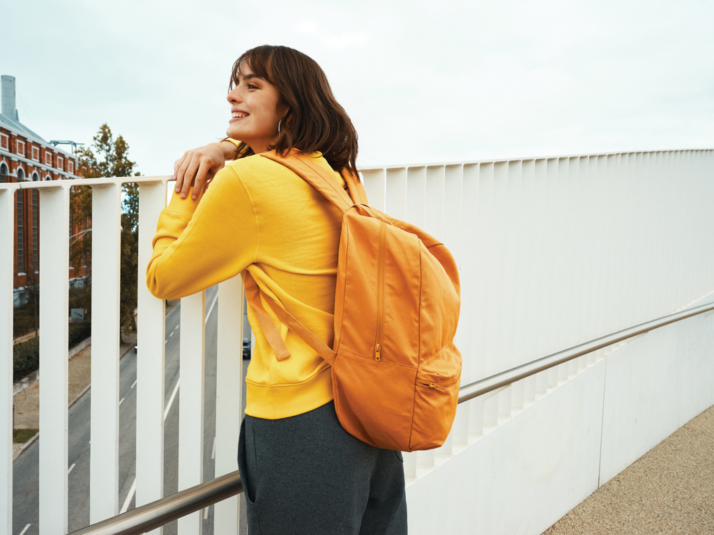 Personne souriante avec sac à dos orange