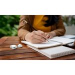Personne écrivant dans un carnet sur une table