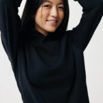 Femme souriante en sweat noir, bras levés
