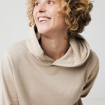 Personne souriante aux cheveux bouclés en sweat beige