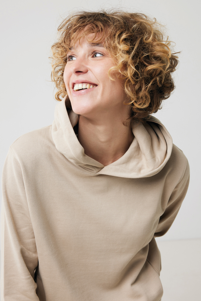 Personne souriante aux cheveux bouclés en sweat beige