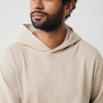 Homme barbu en hoodie beige regardant à gauche