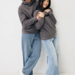 Couple en sweats gris contre un mur