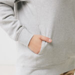 Main dans la poche d’un sweat gris