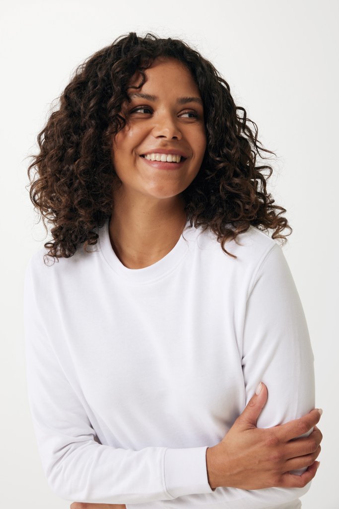Femme souriante aux cheveux bouclés en pull blanc