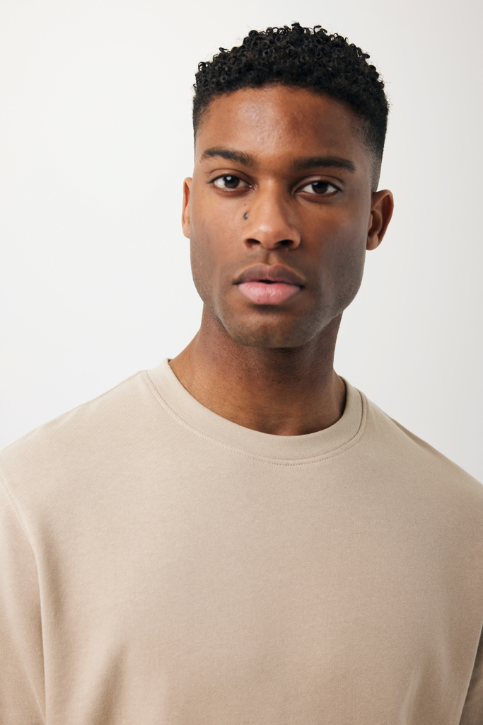 Jeune homme aux cheveux courts bouclés portant sweat beige