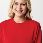 Femme souriante en pull rouge sur fond neutre