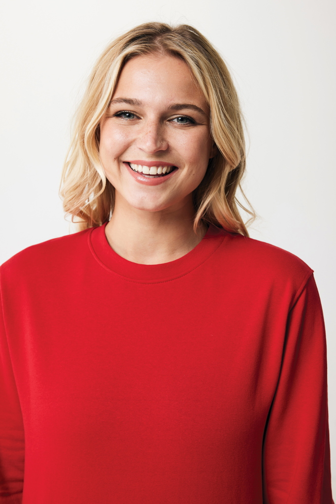 Femme souriante en pull rouge sur fond neutre