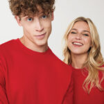 Deux jeunes adultes en pulls rouges souriants