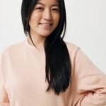 Femme souriante aux cheveux longs portant sweat rose