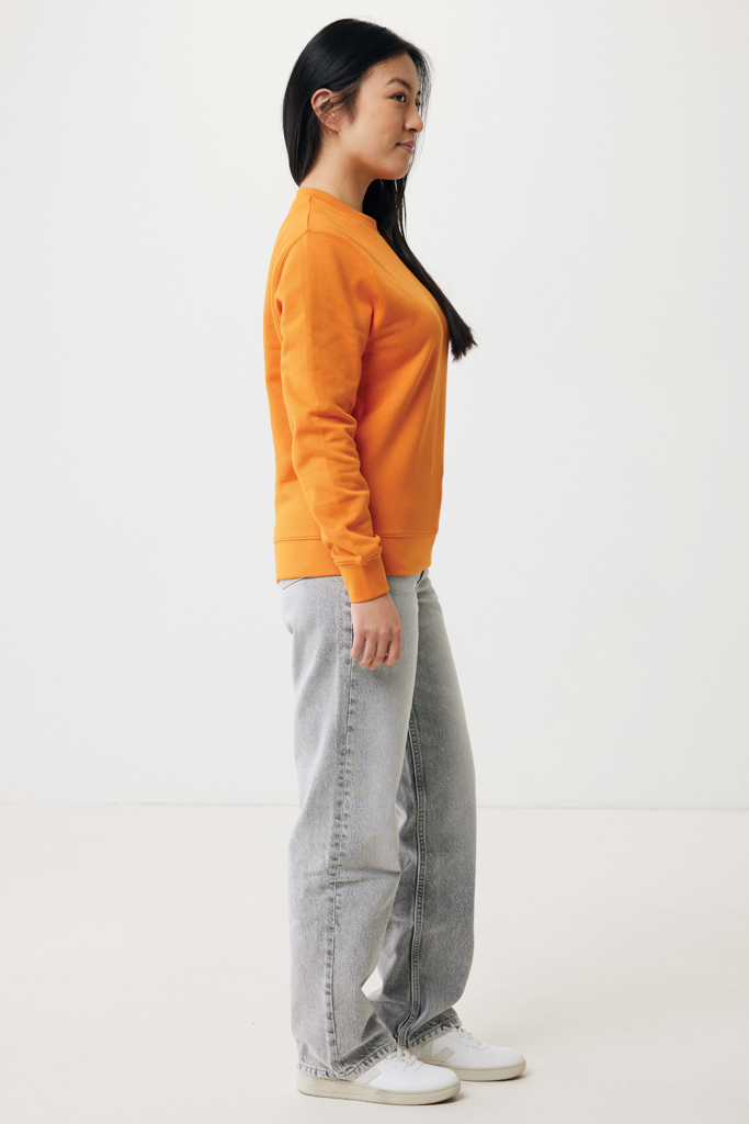 Femme de profil en sweat orange et jean