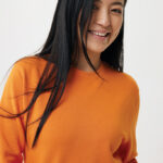 Femme souriante en sweat orange sur fond clair