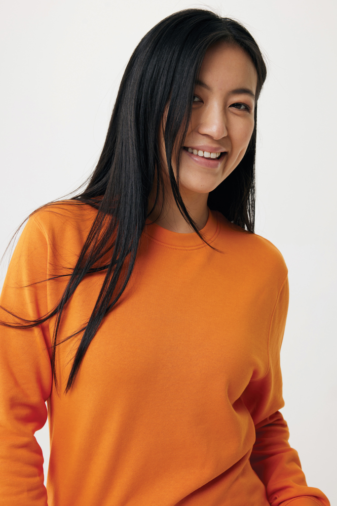 Femme souriante en sweat orange sur fond clair
