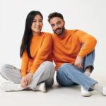 Deux personnes souriantes en pulls orange assises