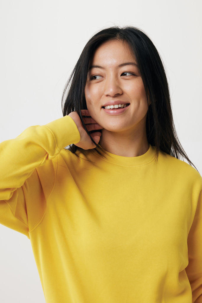 Femme souriante en sweat jaune sur fond neutre