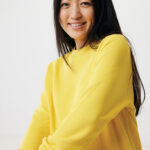 Femme souriante en sweat jaune sur fond neutre