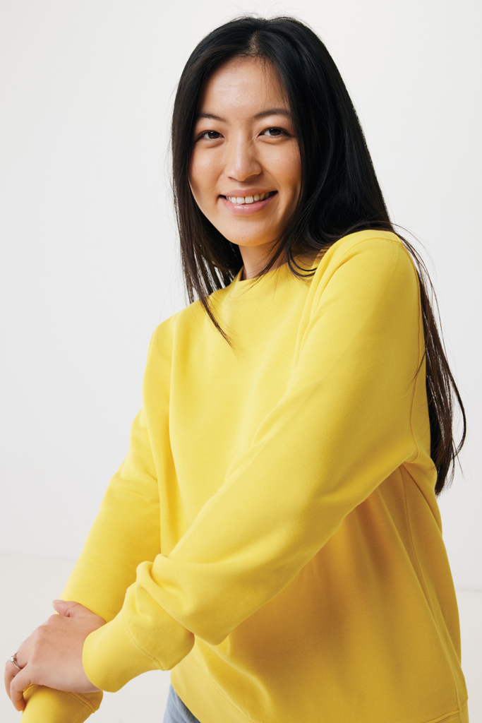 Femme souriante en sweat jaune sur fond neutre