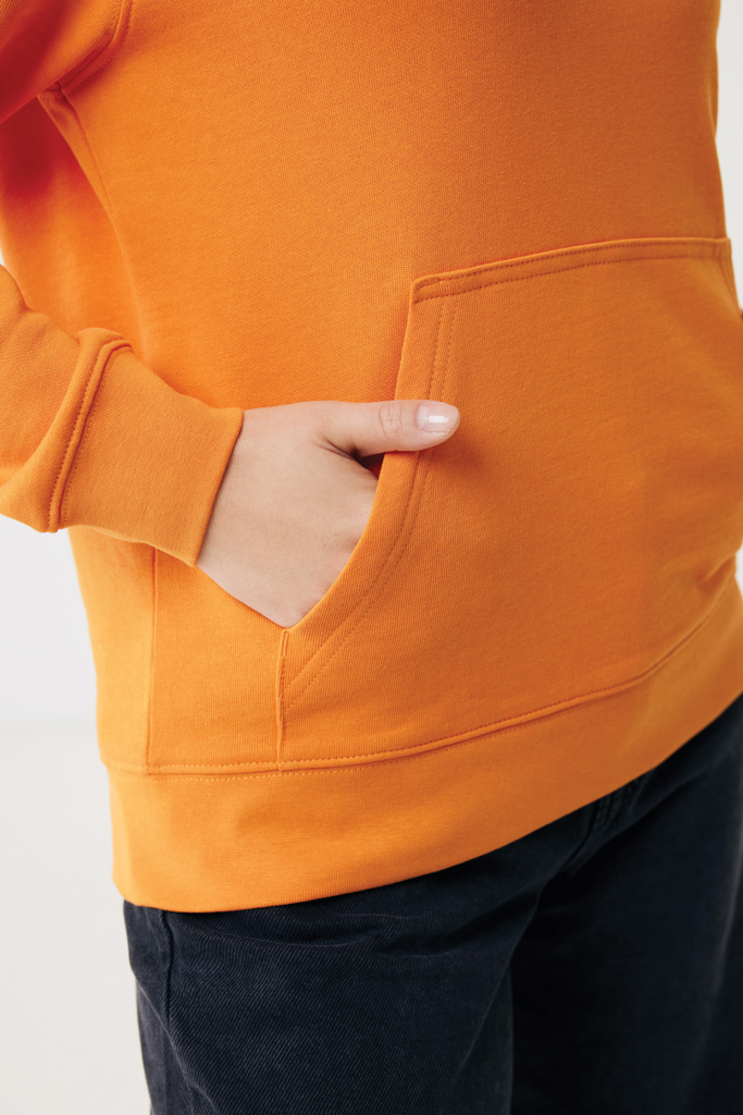 Main dans la poche d’un sweat orange