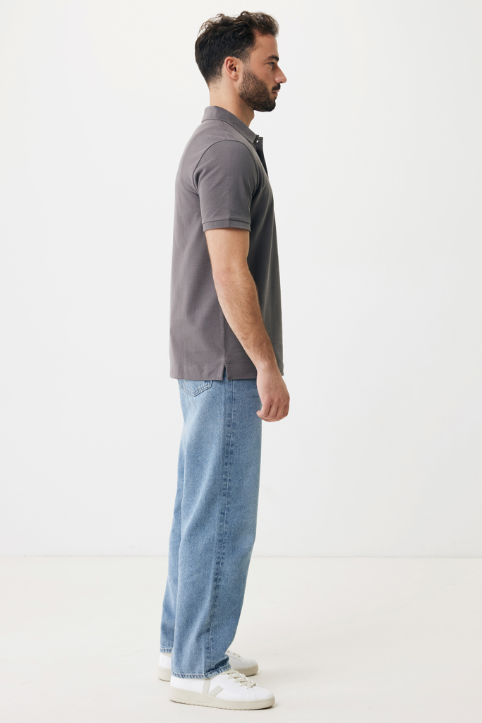 Homme de profil en polo gris et jean