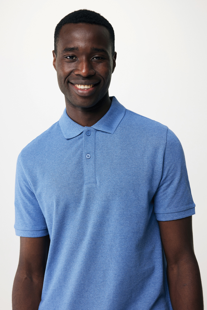Homme souriant en polo bleu sur fond neutre