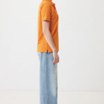 Profil d’une femme en polo orange et jean large